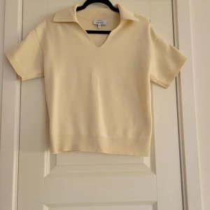 Beige kortärmad tröja från &OtherStories - Säljer en stilren beige tröja med korta ärmar och en snygg v-ringning. Perfekt för en avslappnad look. Tröjan har en ribbad nederkant som ger en fin passform. Passar bra till både jeans och kjol.