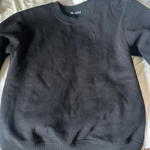 Svart sweatshirt från Zara - En klassisk svart sweatshirt från Zara med rund halsringning och ribbade muddar vid ärmslut och nederkant. Perfekt basic-plagg som funkar till allt och är superenkel att styla. Tillverkad i mjuk bomull för skön känsla hela dagen.