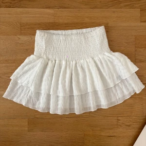 Vit volangkjol  - Superfin vit kortkjol med smock i midjan och dubbla volanger. Så fin att ha på sommaren och passar med allt💞