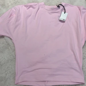 Ljusrosa t-shirt från 157, stl M - Enkel och stilren ljusrosa t-shirt från 157 i storlek M. Klassisk rund halsringning och korta ärmar. Tillverkad i mjuk bomull som känns skön mot huden. Perfekt för en clean och avslappnad look.