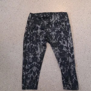 Svarta camo leggings från Yosemite XL - Snygga svarta leggings från Yosemite i storlek XL med grått camo-mönster. Tillverkade i stretchigt material med 81% polyester och 19% elastan. Perfekta för träning eller chill dagar. Croppad längd och bekväm passform.