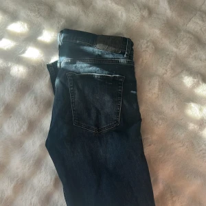 J.Lindeberg Jay jeans midwaist slim - Mörkblå jeans från J.Lindeberg, modell Jay, med midwaist och slim fit. Klassisk femficksdesign, snygga kontrastsömmar och metallknapp framtill. Perfekta för dig som gillar stilrena och moderna jeans med skandinavisk känsla.