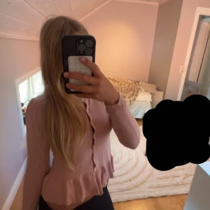 Rosa kofta med pärlor från Pomp de Lux - Supersöt ljusrosa kofta från Pomp de Lux med små pärlor över hela tröjan. Den har långa ärmar, knappar framtill och volang nertill