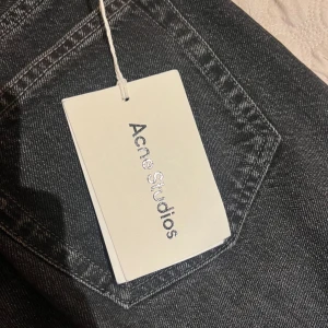 Svarta raka jeans från Acne Studios - Snygga svarta jeans från Acne Studios med klassisk femficksdesign och raka ben. Jeansen har en mörk tvätt och subtila kontrastsömmar. Perfekta för dig som gillar en clean och stilren look. Materialet är robust denim i bomull. Helt nya aldrig använda nypris 3795