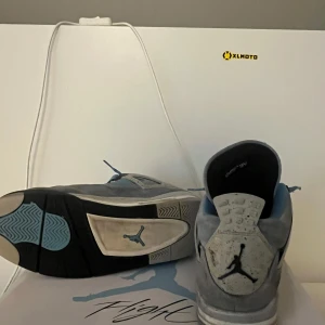 Air Jordan 4 Retro University Blue sneakers - Nike Air Jordan 4 University Blue med grå mocka och blå meshdetaljer. Skorna har svarta och vita inslag på sulan, blå skosnören och tydlig Jumpman-logga på hälen. Tungan har en röd 23-detalj och signaturpatch. Perfekta för dig som vill sticka ut med en ikonisk sneaker.