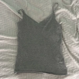 Grå linnetopp med smala axelband - En enkel och stilren grå linnetopp från C med smala axelband och v-ringad hals. 