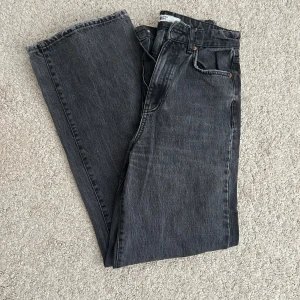 Svarta wide jeans  - Snygga svarta  jeans med rak och bred passform. Klassisk femficksmodell i kraftigt jeanstyg, perfekt för dig som gillar en avslappnad och trendig stil. Tidlös design med knappgylf och cool tvättad look.