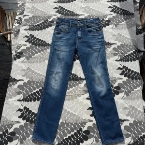 Blåa Replay jeans slim ambrass W28 L30 - Snygga blå jeans från Replay med klassisk femficksdesign och raka ben. Jeansen har diskreta slitningar framtill och bakfickor med dekorativ söm. Tillverkade i mjukt denimtyg som sitter skönt hela dagen.