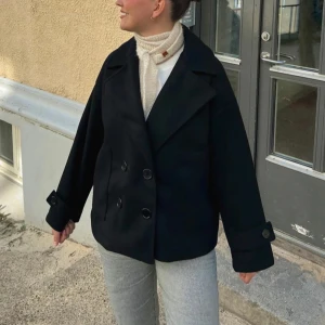 Svart kappa från Design by Si - Stilren svart kappa med dubbelknäppning och bred krage från Design by Si. Lite nopprig därav priset! Strl xs/s