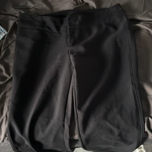 Svarta kostymbyxor från Gina Tricot - Svarta kostymbyxor från Gina Tricot i storlek L. Byxorna har raka ben, knäppning med knappar och dragkedja framtill. Använda 2 gånger cirka. Köpta för 600kr