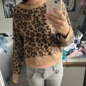 Leopardmönstrad stickad tröja från H&M - Säljer en snygg stickad tröja från H&M i storlek S med leopardmönster. Tröjan är beige med bruna och svarta detaljer, har rund halsringning och långa ärmar. 