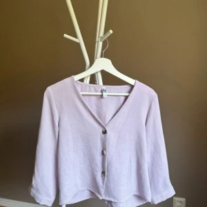 Ljuslila kofta från JDY med knappar - ❤️bilder från min Vinted ❤️Superfin ljuslila kofta från JDY med tre stora knappar framtill och v-ringad hals. Koftan har trekvartsärmar och är gjord i ett mjukt, lätt material som känns skönt mot huden. Perfekt att slänga över en topp för en chill look.