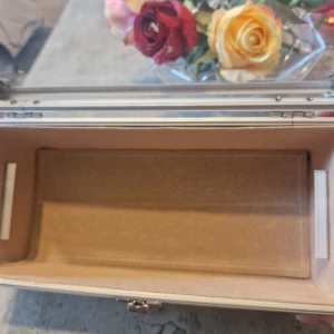 Beige och brun smyckeskrin - Snygg smyckeskrin i beige och brunt med mönster. Skrinet har silverfärgade metalldetaljer, genomskinligt lock och robust ram. Perfekt för att förvara smink, accessoarer eller småprylar. Låsbar för extra säkerhet och stilren look. Har lite skavanker och skador på vissa ställen kolla bild. Inget som märks.