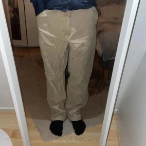 Double knee  - Säljer ett par beige cargopants med flera praktiska fickor. Byxorna har en normal passform och är perfekta för en avslappnad stil. De är tillverkade i ett slitstarkt material och har knappar som detalj.