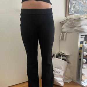 Kostymbyxor med bootcut - Snygga svarta byxor från Gina Tricot med bootcut-stil. De är högmidjade och har en elegant passform som passar perfekt för en trendig look. Perfekta för både vardag och speciella tillfällen.