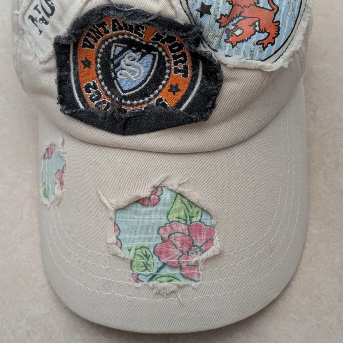 Beige keps med patchar och blommigt mönster