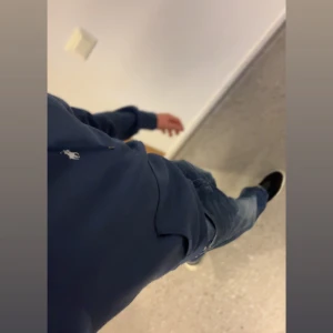 Polo Ralph Lauren Hoodie - Säljer en klassisk blå hoodie från Polo Ralph Lauren med vit broderad logga på bröstet. Tröjan har huva med dragsko och en stor magficka. Perfekt för en avslappnad och stilren look.