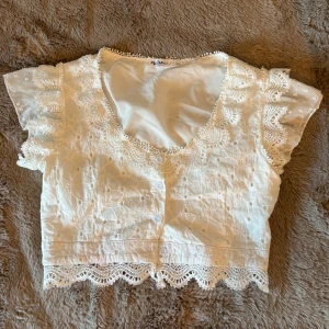 Vit blus med spets från Flam Mode - Superfin vit, croppad blus från Flam Mode med spetsdetaljer och korta ärmar. Perfekt för sommarens alla tillfällen! Använd 2 gånger och inga defekter🌸🫶🏼