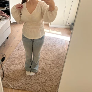Beige blus - Säljer en beige blus med v-ringning. Blusen har resår vid vissa ställen. Materialet är lätt strukturerat och ger en luftig känsla. Perfekt till jeans eller kjol! Väldigt fin till sommaren och nu på våren. Aldrig använt.