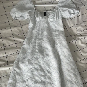 Snygg klänning - Säljer denna snygga klänning från HM. Den är vit med små blå blommor. Använd fåtal gånger och är därför i mycket bra skick. I storlek XXS. 🥰Har dragkedja vid sidan som inte syns alls när den är stängd.