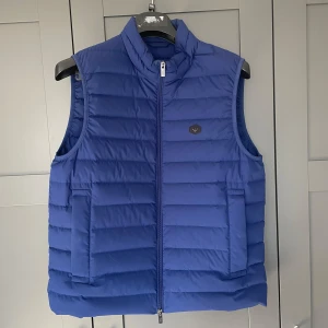 Armani Väst - Säljer nu en blå dunväst från Emporio Armani i 100% polyester. Västen är i ett väldigt lätt material som gör att västen känns som luft💨. Den är i ett väldigt bra skick och är använd ett få tal gånger. Den är i storleken M och sitter regular. Tveka inte på att fråga om mer info eller liknande