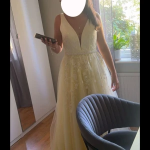 Balklänning  - Jätte fin ljusgul lång balklänning med djup v-ringning och spetsdetaljer upptill. Klänningen har markerad midja med pärlband, lätt utställt kjolparti med blommigt mönster. Perfekt för bal eller student❤️ Hör av er ifall ni har frågor om mått osv