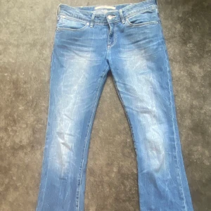 Blå bootcut jeans från Wrangler - Säljer ett par klassiska snygga blå bootcut jeans från Wrangler. Jeansen har snygga fickor med ett litet mönster och normal passform, perfekt för dig som gillar en tidlös denimlook. Storlek 28/32