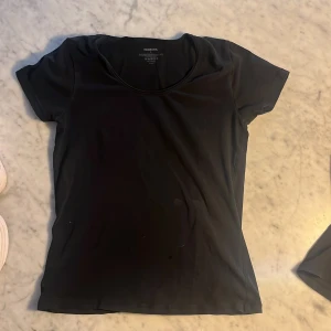 2 Svarta t-shirts från Newbody - En klassisk svart t-shirt från Newbody i mjuk bomullsblandning. Modellen har rund halsringning och korta ärmar, perfekt för en enkel och stilren look. Passformen är normal och materialet känns skönt mot huden.