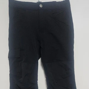 Svarta vattenavvisande byxor från Lindex Kids - Svarta byxor från Lindex Kids med vattenavvisande material. Byxorna har en enkel design med knapp i midjan och fickor på sidorna, perfekta för utomhusaktiviteter. Passar barn ca 9-10 år.