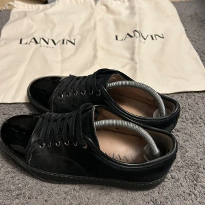 Svarta sneakers från Lanvin - Snygga svarta sneakers från Lanvin. Storlek 43. Jag har tagit hand om dem bra skick inga defekter två dust bags med följer även kartong med de grejerna som sitter i skorna på bilden. De är bara att höra av sig om man är intresserad pris är ej hugget i sten vid snabb affär.