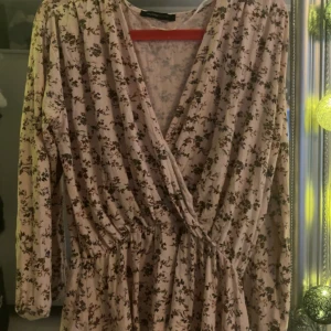 Blommig omlottstopp med lång ärm - Säljer en  omlottkstopp med långa ärmar och resår i midjan med blommdetaljer 