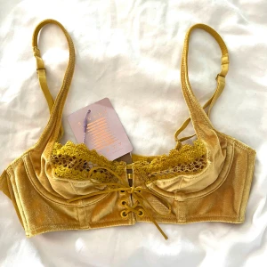 Fenty Velvet BH Oanvänd - Jättttesnygg bh i sammet från Fenty. Speciell guld / gul färg och med spets och snörning. Helt oanvänd med lappar kvar då den ej passade mig. 