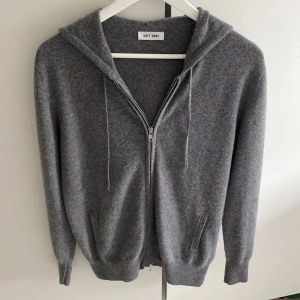 Grå kashmir hoodie från Soft Goat - Mysig grå hoodie från Soft Goat i 100% kashmir. Tröjan har dragkedja framtill, huva med snören och ribbade muddar. Perfekt till sommarn och hösten. I mycket bra skick och är perfekt i storleken. Nypris 3000kr mitt pris 1499kr