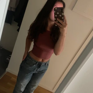 Rosa croppad ribbad linnetopp - Säljer en snygg croppad linnetopp i en dämpad rosa nyans. Toppen är ribbad och ärmlös med en tight passform, perfekt till jeans eller kjol. Enkel och stilren design som är lätt att matcha.