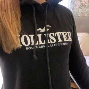Hollister Hoodie - ‼️TVÄTTAR PLAGGET DAGEN DU KÖPER‼️  Superskön och snygg  hoodie från Hollister, med den klassiska loggan och "Southern California" text framtill. Färgen är svart och materialet är mjukt och bekvämt perfekt för både en vanlig skoldag eller vardag och mys. Den sitter riktigt snyggt på mig som vanligtvis bär storlek XS/S.  Hoodien är i bra skick utan hål eller fläckar. Ena snöret är lite längre än det andra, vilket faktiskt ger en lite avslappnad och cool look!