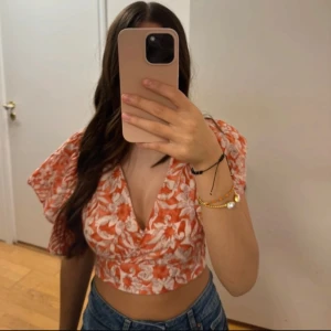Blommig croppad omlottopp orange/vit - Fin croppad blus från Zara, storlek xs men något tightare än vanligt. Använd 1 gång så den är i bra skick.