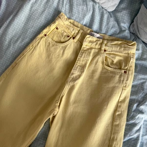 Ljusgula raka jeans från Zara - Säljer ett par ljusgula jeans från Zara med raka ben och råa kanter nertill. Byxorna har klassisk femficksdesign, bälteshällor och är tillverkade i bomull. Perfekta för dig som vill sticka ut med färg i vardagen.