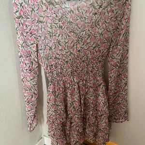 Blommig klänning från Zara - Supersöt klänning från Zara med smockad midja! Och en fin v ringning. Jag säljer pga att den är lite för tajt för mig!