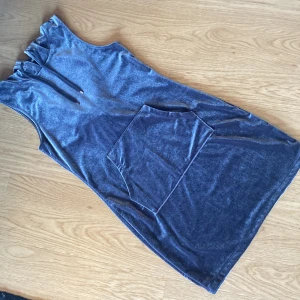 Armlös klänning i velour från Bik Bok storlek S - Kort armlös klänning i velour från Bik Bok. Klänningen har luva med snörning och stor ficka framtill. 