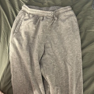 Grå mjukisbyxor från Iconic Sportswear - Mysiga grå mjukisbyxor från Iconic Sportswear i storlek S. Byxorna har resår och snörning i midjan samt två sidofickor. Perfekta för chill eller träning, tillverkade i mjukt bomullsmaterial för extra komfort.