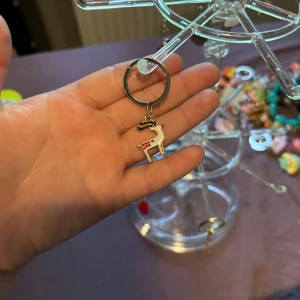 Nyckelring med vit ren och röda detaljer - Söt nyckelring med en vit ren i metall, dekorerad med små röda prickar och svarta horn. Perfekt accessoar till väskan eller nyckelknippan för dig som gillar gulliga detaljer och vinterkänsla.