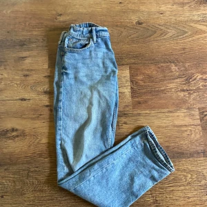 Ljusblå raka jeans i storlek 170 - Säljer ett par klassiska ljusblå jeans med raka ben och normal passform. Jeansen har fem fickor och bälteshällor, perfekta för en avslappnad och stilren look. Passar dig som är 14 år och äldre.