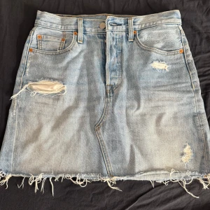 Levi's ljusblå jeanskjol med slitningar - Ljusblå jeans kjol ifrån Levi’s. Använt ett få tal ggr o inga defekter 