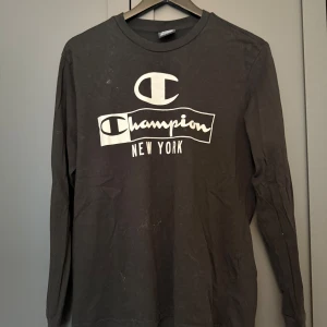 Svart långärmad tröja Champion S - Svart långärmad tröja från Champion med stort vitt tryck på bröstet där det står 'Champion New York'.