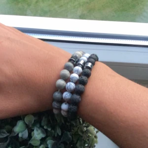 Stilrena armband med stenar - Tre armband med runda pärlor i svart, grått och vitt. Pärlorna är av sten och lavasten, vissa med marmorerat mönster. Snyggt att bära tillsammans för en cool och naturlig look som lägger till de lilla extra. Armbanden säljs styckvis. Priset är inte hugget i sten vid snabb affär, vid fler köp blir det billigare!
