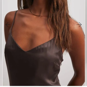 Brun satinklänning - Elegant brun långklänning i satin med smala axelband och v-ringad hals. Säljer då den inte längre kommer till användning, använd vid 1 tillfälle. slutsåld på hemsidan, nypris 499kr