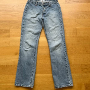 Dolce & Gabbana raka jeans i ljusblå denim - Snygga ljusblå jeans från Dolce & Gabbana med raka ben och klassisk femficksdesign. Jeansen har knäppning med tre synliga metallknappar och bälteshällor. Perfekta för dig som gillar en tidlös och avslappnad look. Low waisted och köpt vintage.