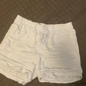 Ljusblå linneshorts från H&M - Snygga ljusblå shorts från H&M i linne med normal passform. De har resår och snörning i midjan samt fickor både fram och bak. Perfekta för varma dagar och enkel stil. Kontakta för fler bilder🌟