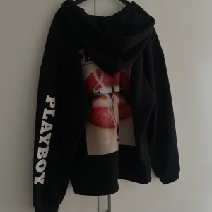 Svart hoodie med tryck från Playboy x Moschino - Svart hoodie med dragkedja från Playboy x Moschino. Oversized passform och mjukt material. I storlek XS men känns som en M! 