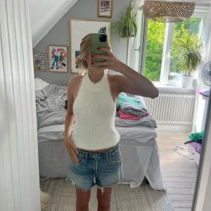 Vit stickad halterneck linnetopp - Säljer en vit stickad halterneck linnetopp med öppen rygg. Toppen är ärmlös och har en croppad passform, perfekt för varma dagar. Mjuk och skön mot huden.